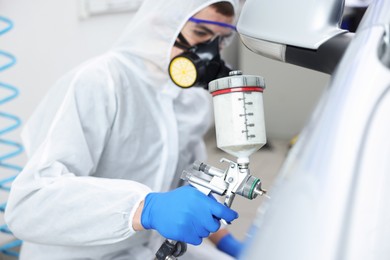 Photo of Worker painting car in body shop, selective focus