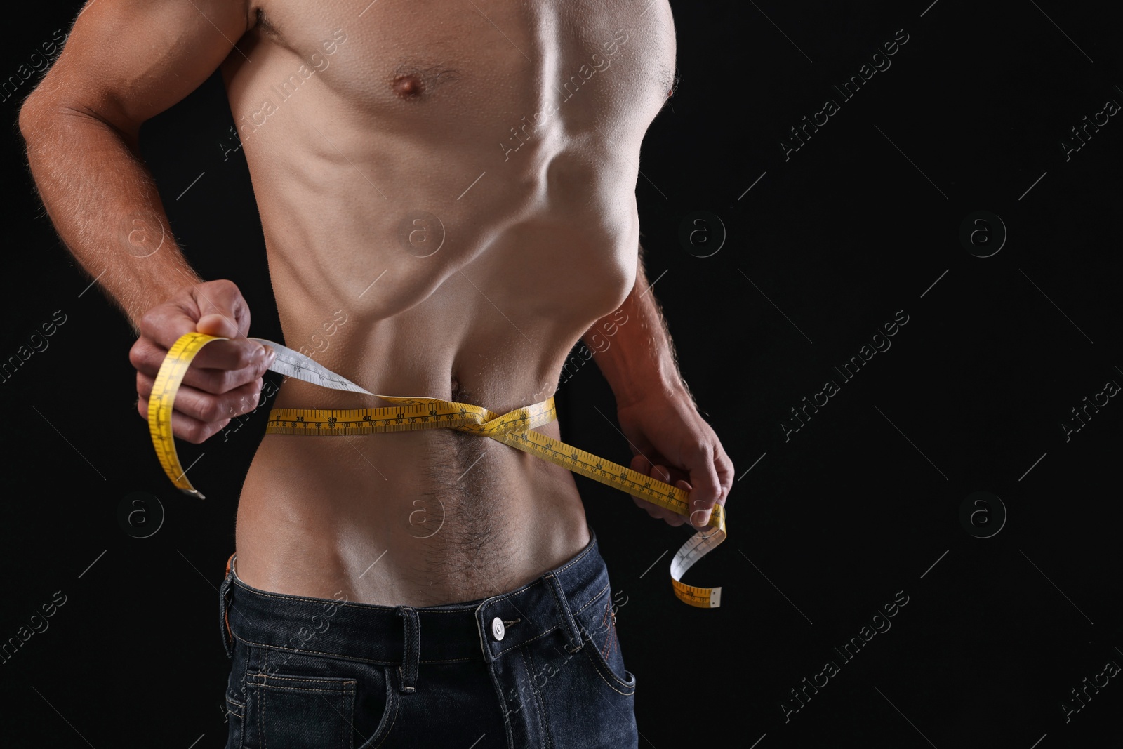 Anorexic man measuring his waist on black background, closeup. Space for text Photo of Anorexic man measuring his waist on black background, closeup. Space for text