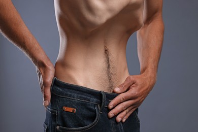 Photo of Man suffering from anorexia on grey background, closeup