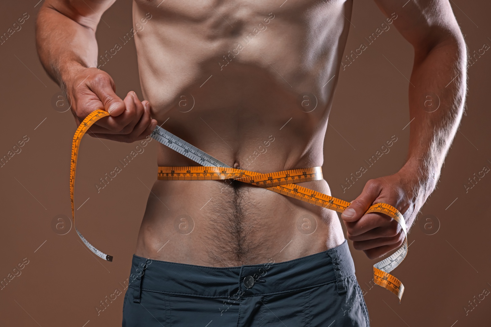 Anorexic man measuring his waist on beige background, closeup Photo of Anorexic man measuring his waist on beige background, closeup