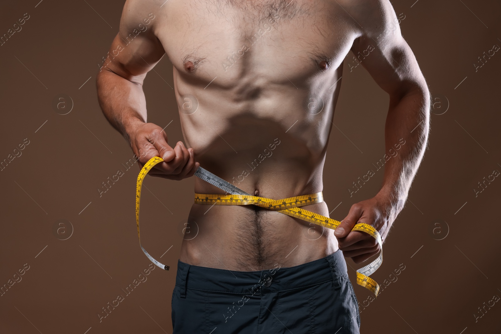 Anorexic man measuring his waist on beige background, closeup Photo of Anorexic man measuring his waist on beige background, closeup