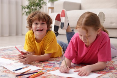 Photo of Cute kids learning to draw on floor at home