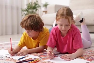 Photo of Cute kids learning to draw on floor at home