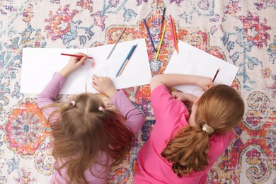 Photo of Cute kids learning to draw on floor at home, top view