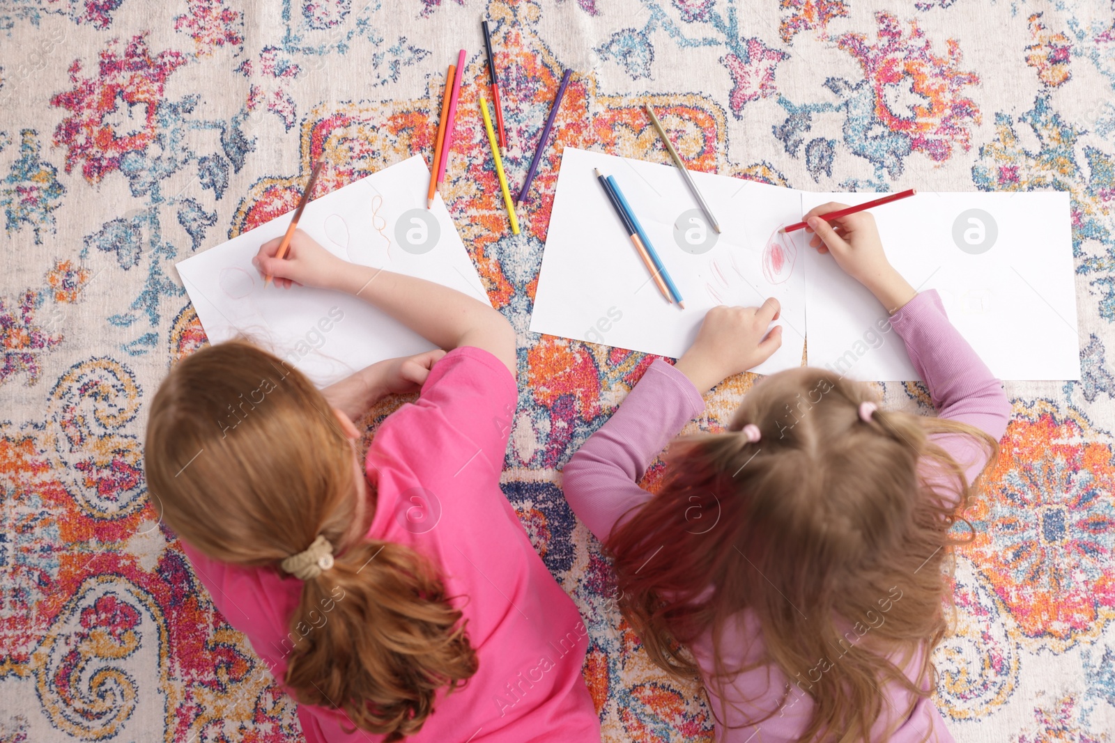Photo of Cute kids learning to draw on floor at home, top view