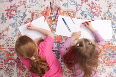 Photo of Cute kids learning to draw on floor at home, top view