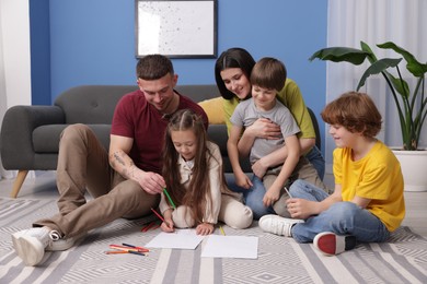 Photo of Parents teaching their kids to draw on floor at home