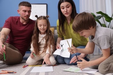 Photo of Parents teaching their kids to draw on floor at home