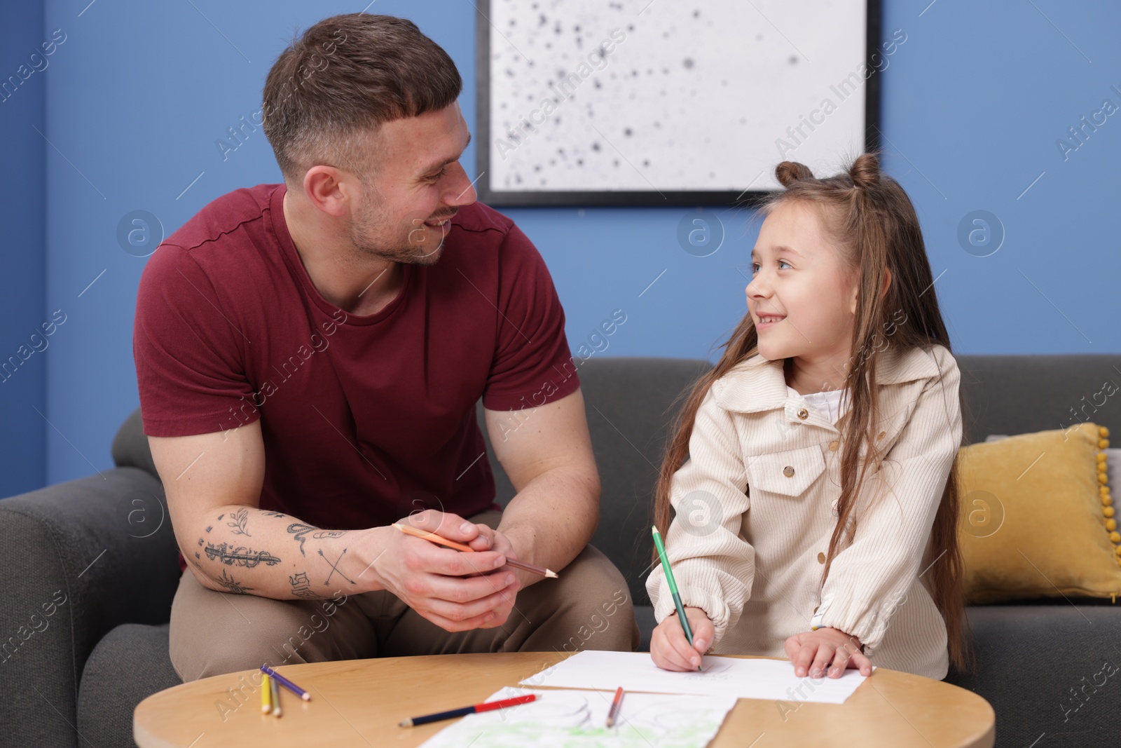 Father teaching his daughter to draw at table indoors Photo of Father teaching his daughter to draw at table indoors