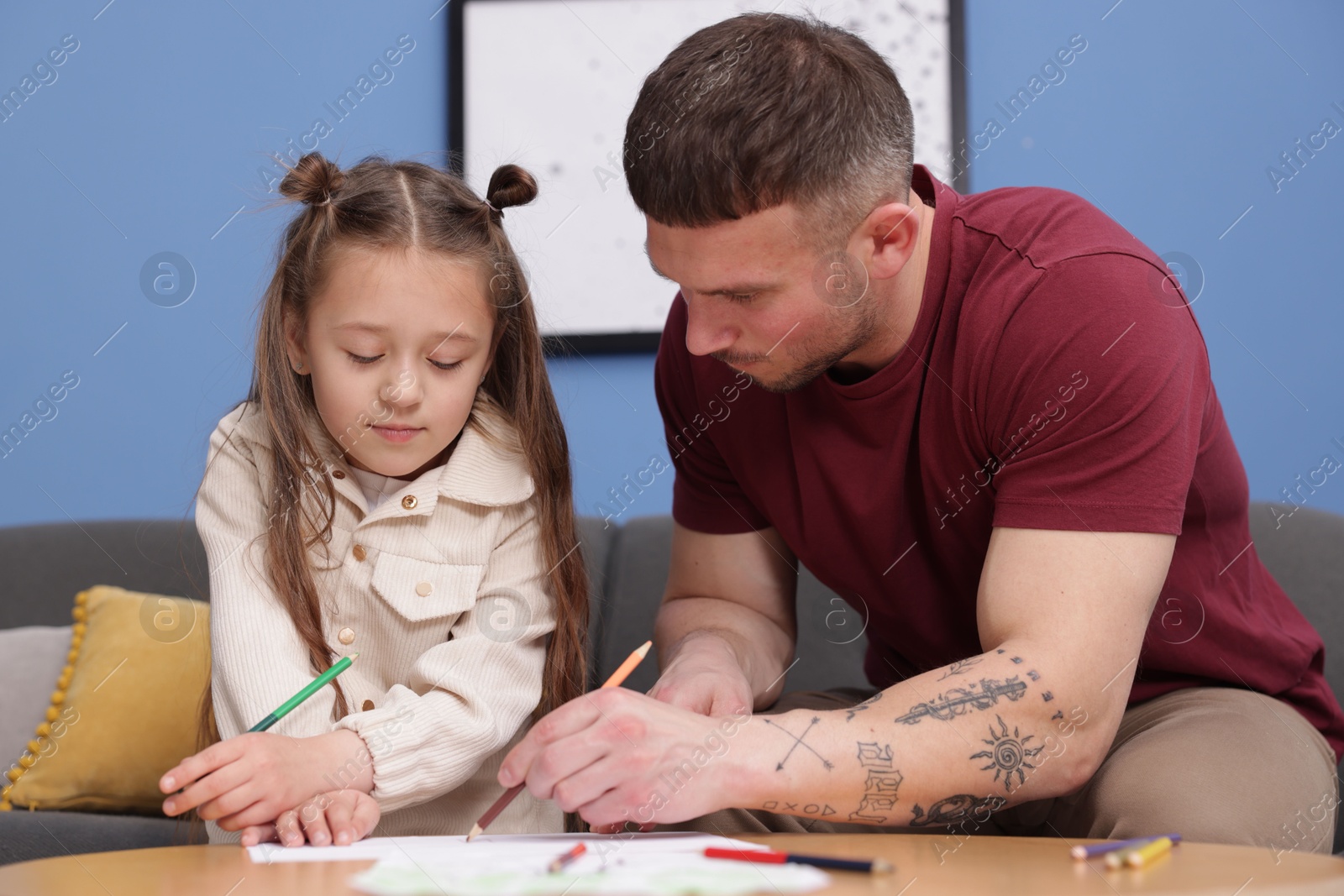 Father teaching his daughter to draw at table indoors Photo of Father teaching his daughter to draw at table indoors