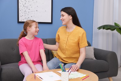 Photo of Mother teaching her daughter to draw at table indoors
