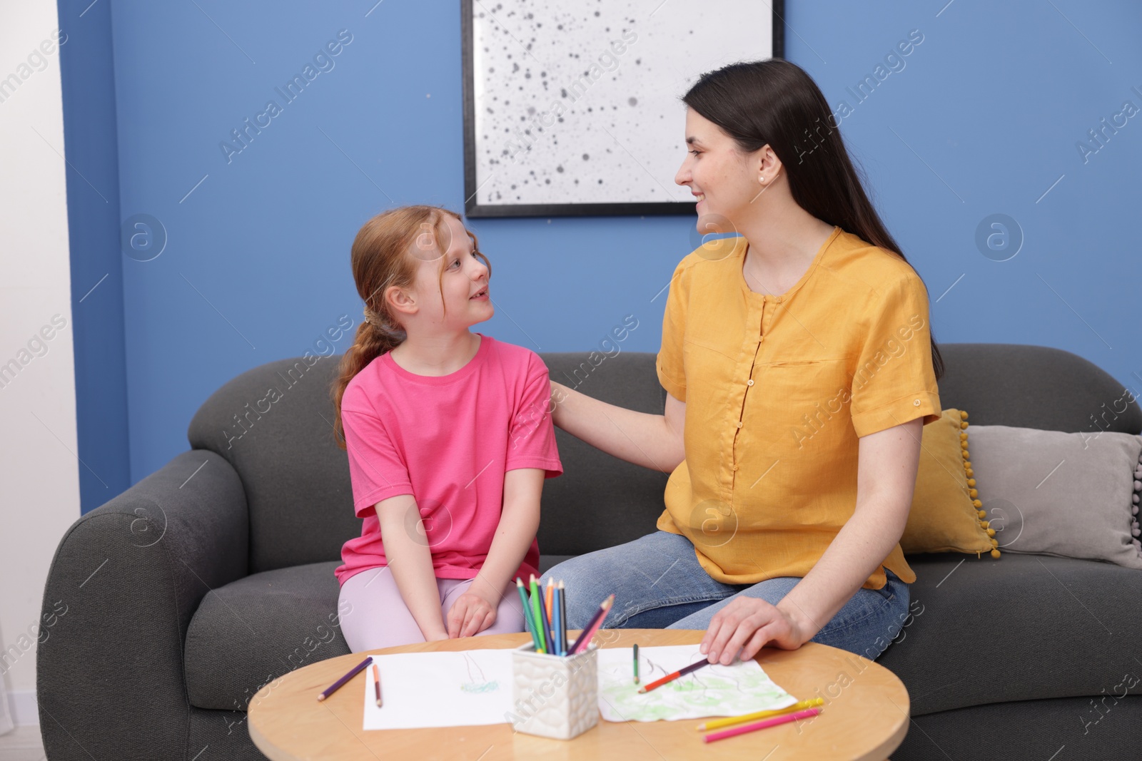 Mother teaching her daughter to draw at table indoors Photo of Mother teaching her daughter to draw at table indoors