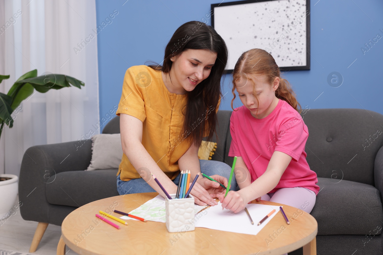Mother teaching her daughter to draw at table indoors Photo of Mother teaching her daughter to draw at table indoors