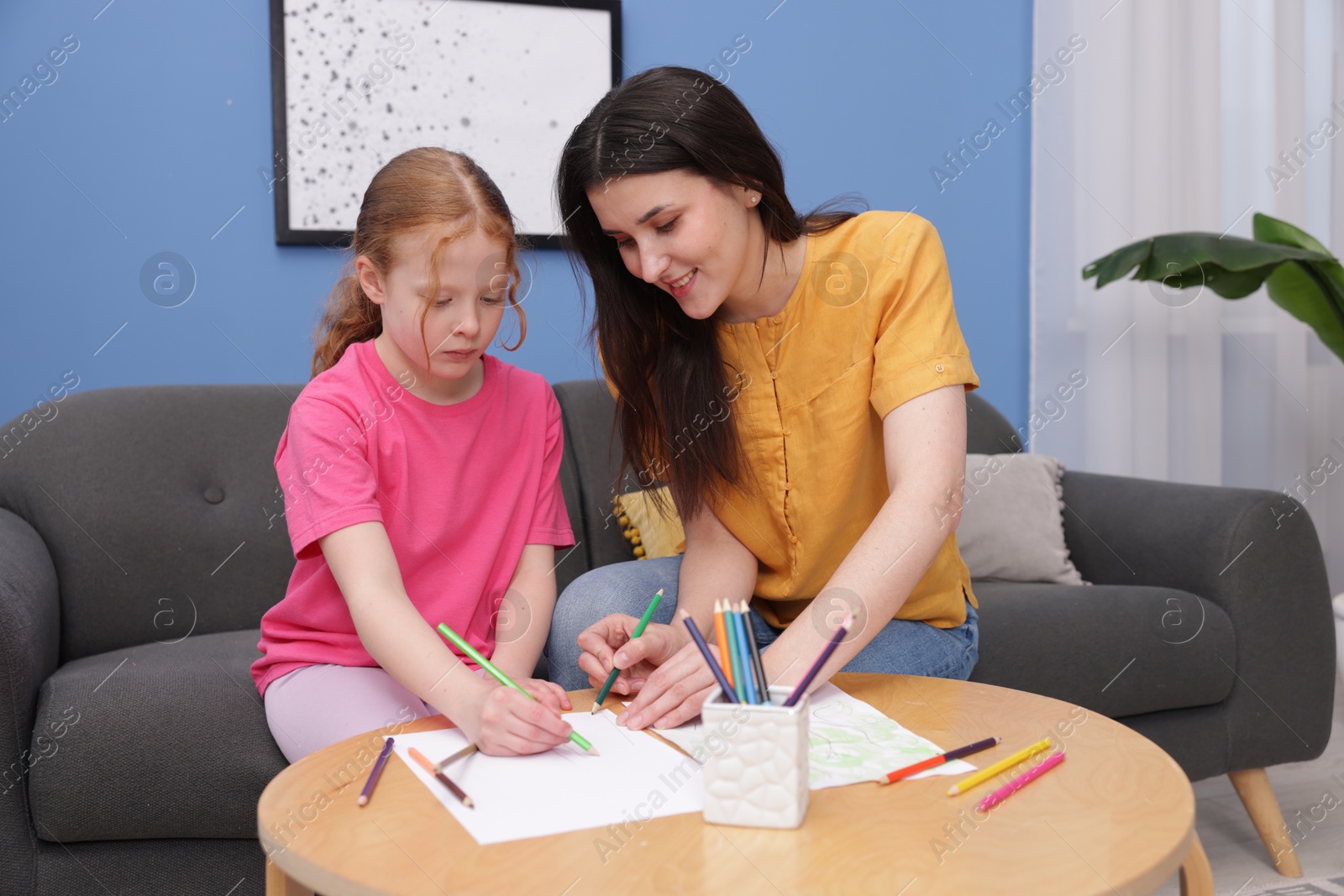 Mother teaching her daughter to draw at table indoors Photo of Mother teaching her daughter to draw at table indoors