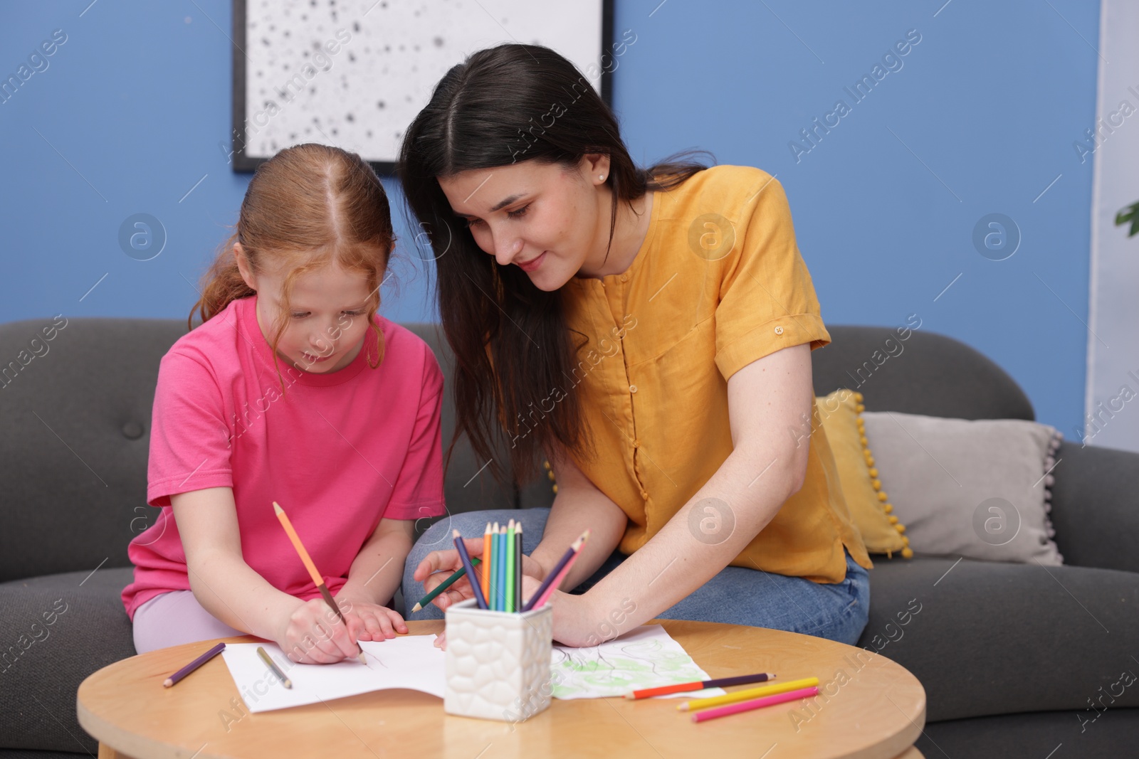 Mother teaching her daughter to draw at table indoors Photo of Mother teaching her daughter to draw at table indoors
