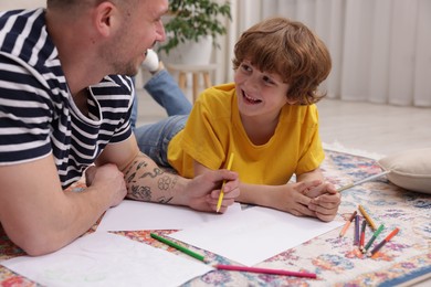 Photo of Father teaching his son to draw on floor at home