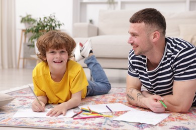 Photo of Father teaching his son to draw on floor at home