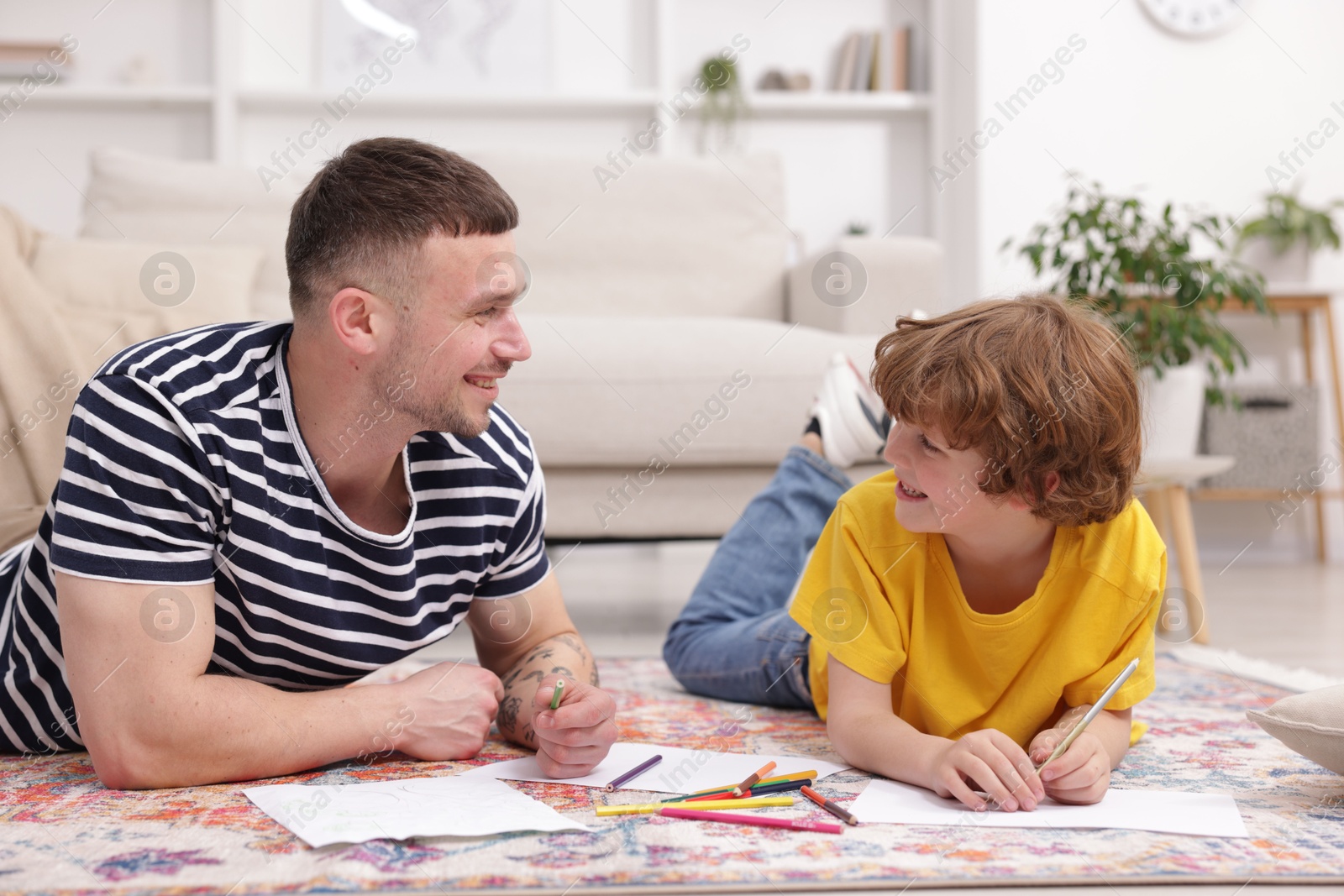 Father teaching his son to draw on floor at home Photo of Father teaching his son to draw on floor at home