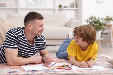 Photo of Father teaching his son to draw on floor at home