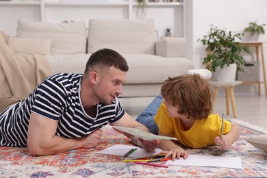 Photo of Father teaching his son to draw on floor at home