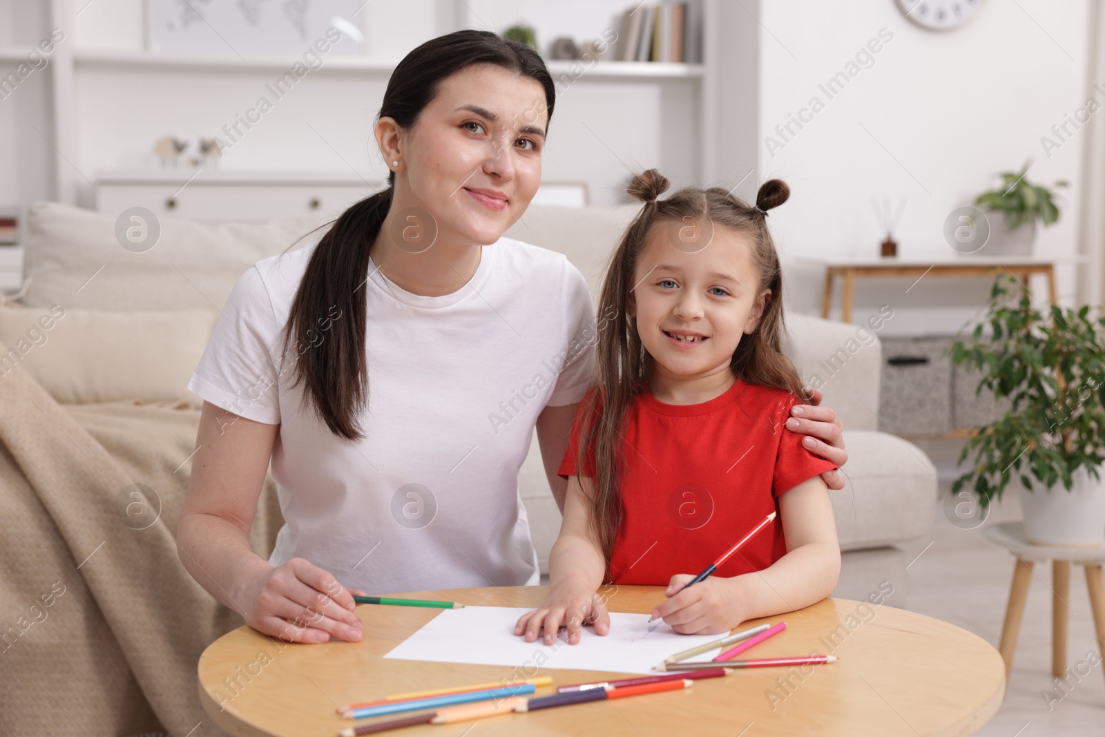 Mother teaching her daughter to draw at table indoors Photo of Mother teaching her daughter to draw at table indoors