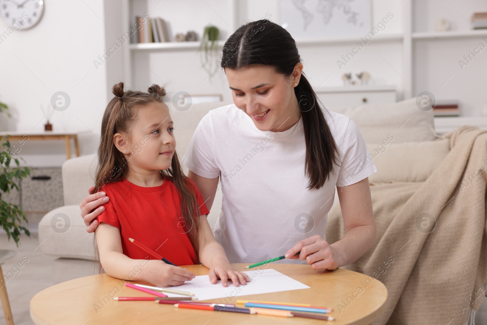 Mother teaching her daughter to draw at table indoors Photo of Mother teaching her daughter to draw at table indoors