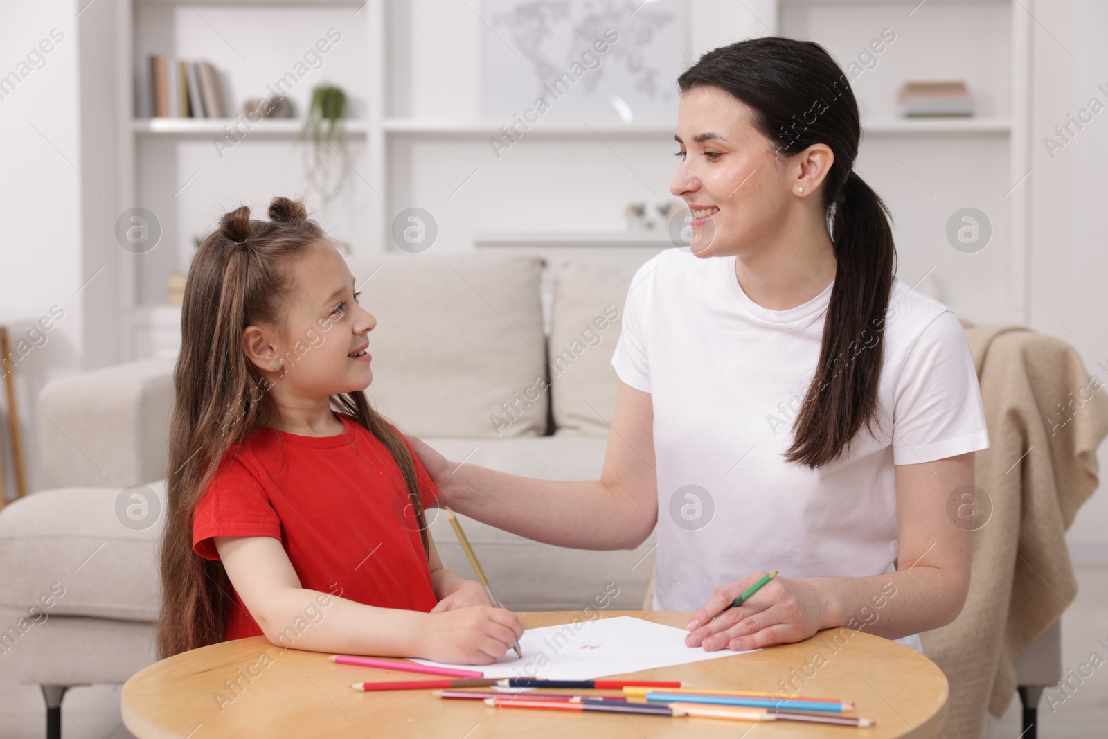 Mother teaching her daughter to draw at table indoors Photo of Mother teaching her daughter to draw at table indoors