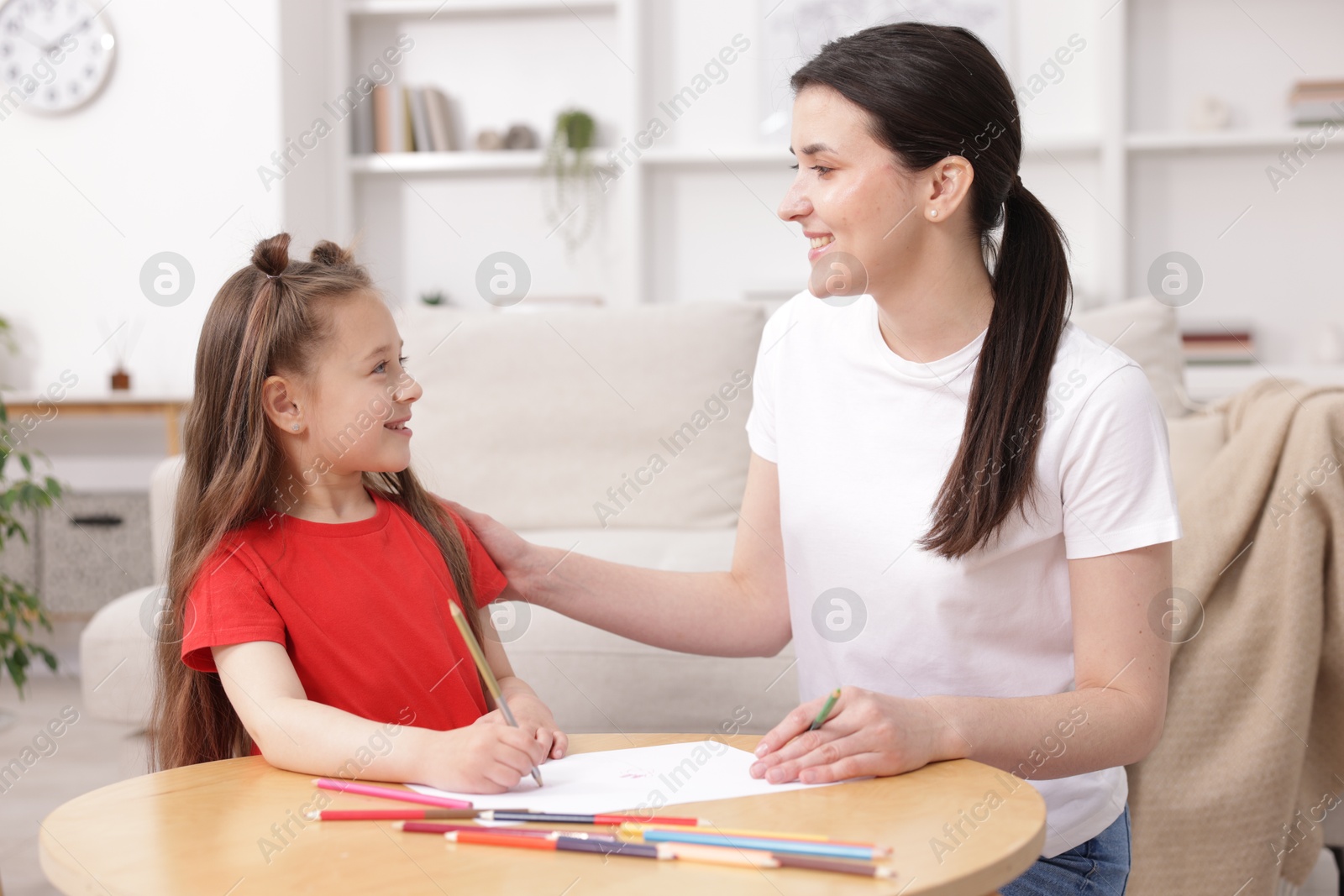 Mother teaching her daughter to draw at table indoors Photo of Mother teaching her daughter to draw at table indoors