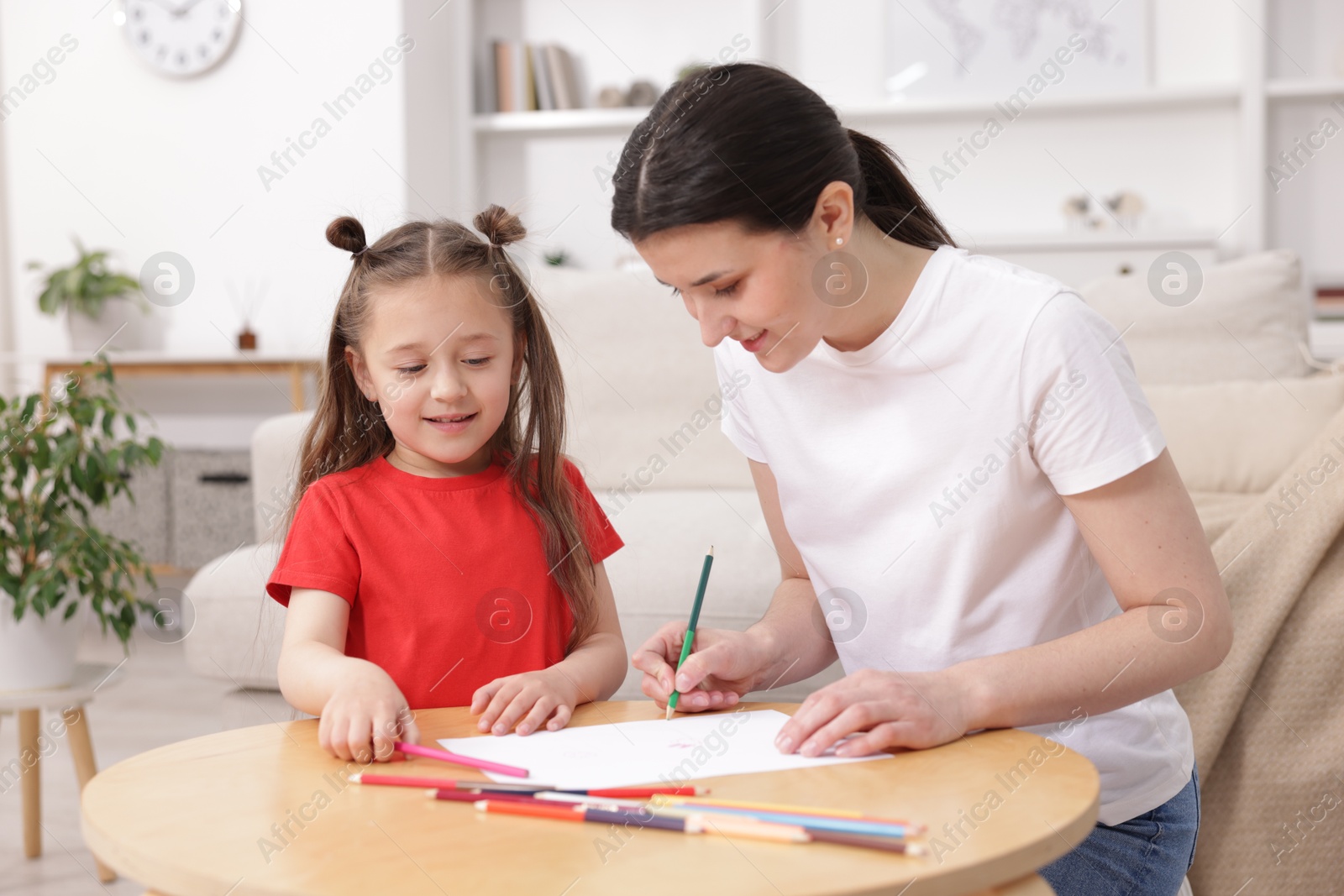 Mother teaching her daughter to draw at table indoors Photo of Mother teaching her daughter to draw at table indoors