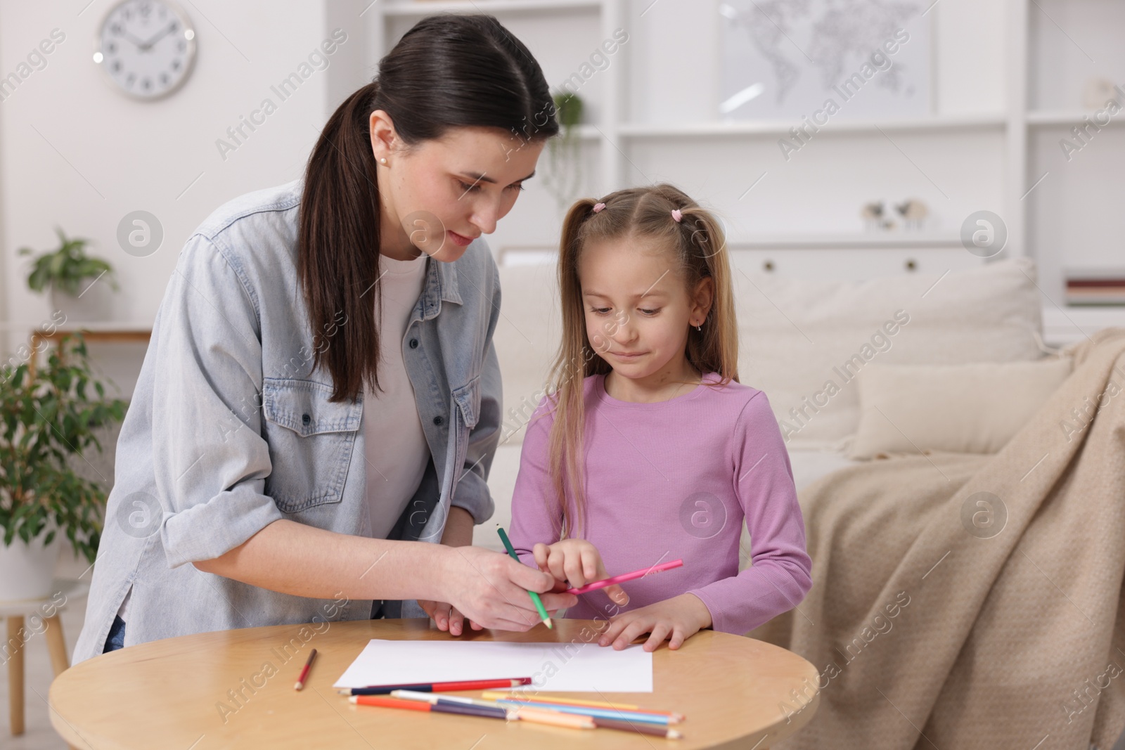 Photo of Mother teaching her daughter to draw at table indoors, space for text