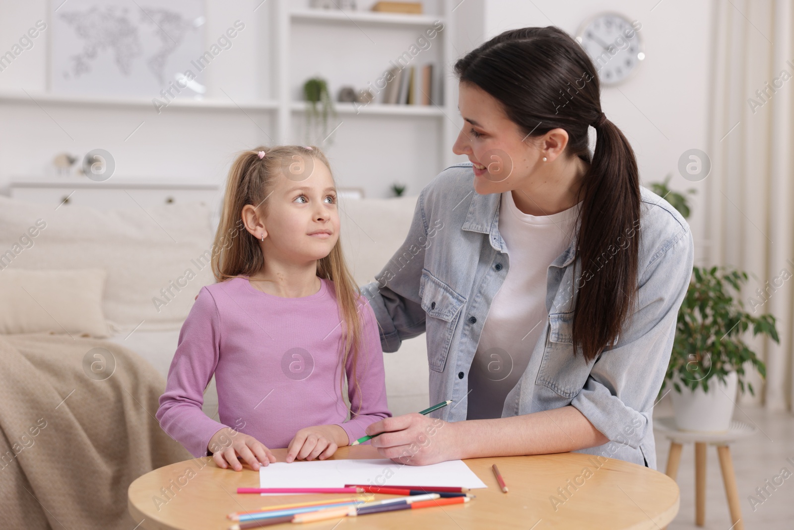 Mother teaching her daughter to draw at table indoors Photo of Mother teaching her daughter to draw at table indoors