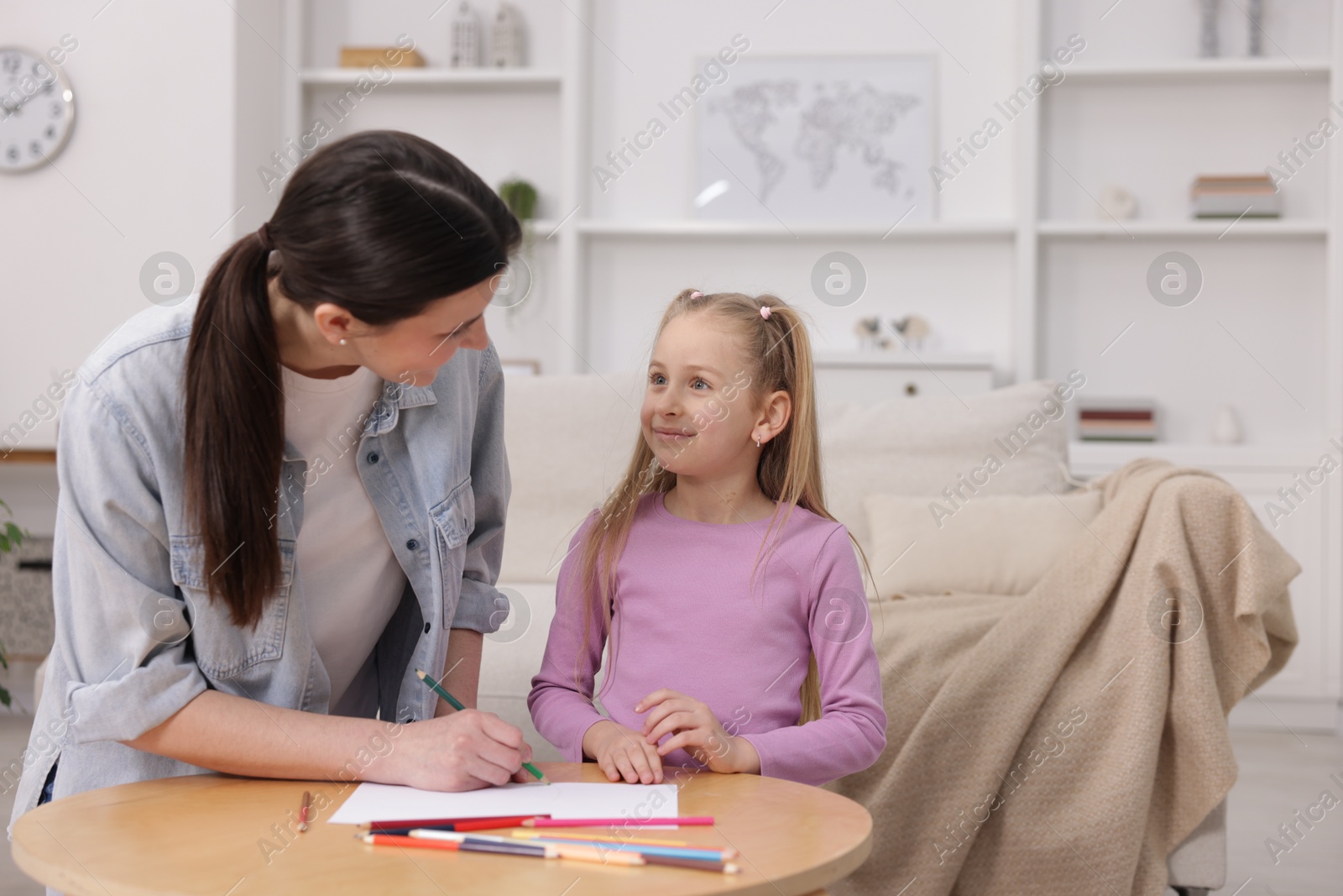 Mother teaching her daughter to draw at table indoors, space for text Photo of Mother teaching her daughter to draw at table indoors, space for text