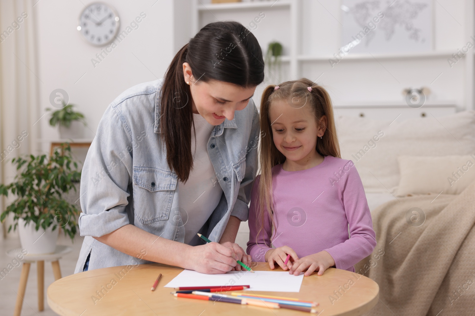 Mother teaching her daughter to draw at table indoors Photo of Mother teaching her daughter to draw at table indoors