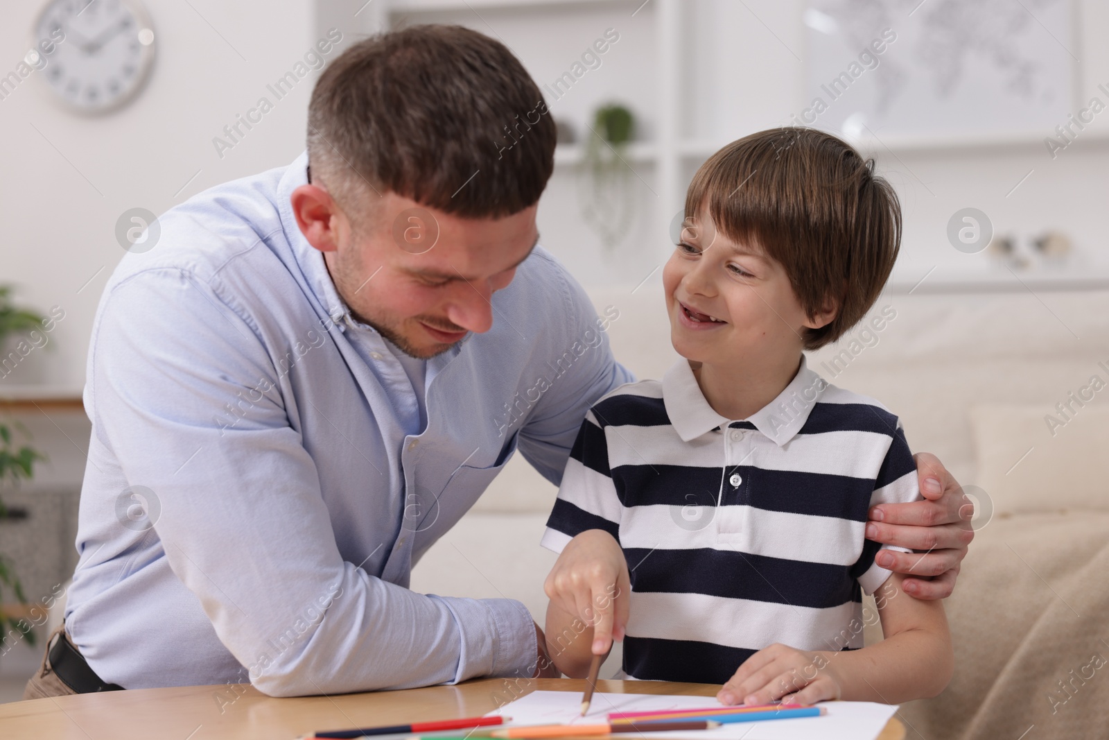 Father teaching his son to draw at table indoors Photo of Father teaching his son to draw at table indoors