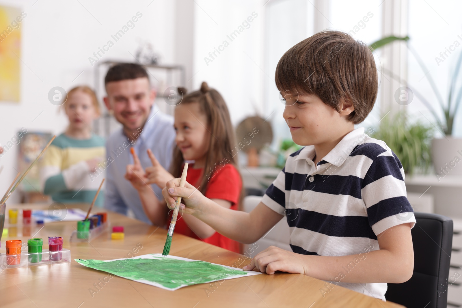 Kids with teacher at painting lesson, selective focus. Learning to draw Photo of Kids with teacher at painting lesson, selective focus. Learning to draw