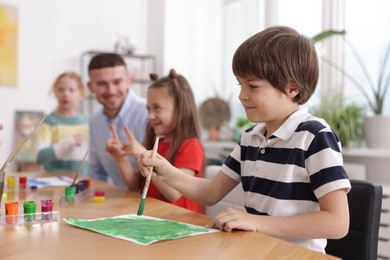 Photo of Kids with teacher at painting lesson, selective focus. Learning to draw