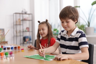 Photo of Kids painting at table indoors, selective focus. Learning to draw