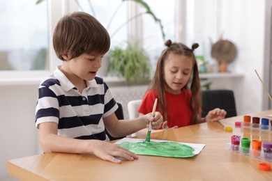 Photo of Kids painting at table indoors, selective focus. Learning to draw