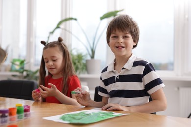Photo of Kids painting at table indoors. Learning to draw