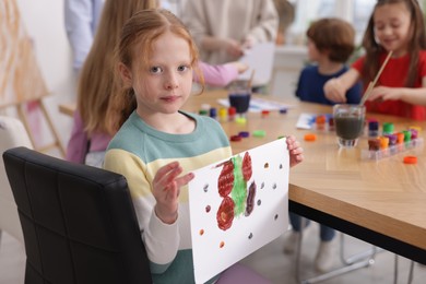 Photo of Cute little girl showing her painting at lesson indoors, selective focus. Learning to draw