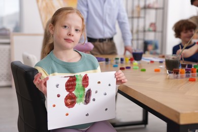Photo of Cute little girl showing her painting at lesson indoors, selective focus. Learning to draw