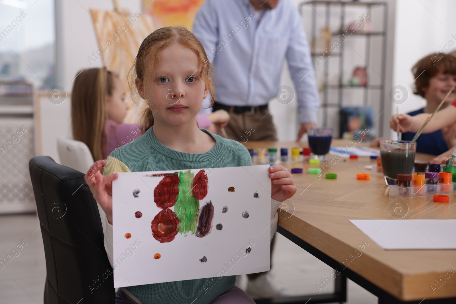 Cute little girl showing her painting at lesson indoors, selective focus. Learning to draw Photo of Cute little girl showing her painting at lesson indoors, selective focus. Learning to draw