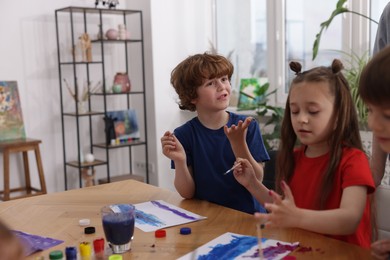 Photo of Kids painting at table indoors. Learning to draw
