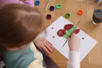 Photo of Little girl painting at table indoors, above view. Learning to draw