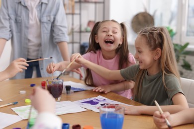Photo of Kids with teacher at painting lesson indoors. Learning to draw