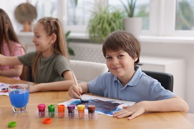 Photo of Kids painting at table indoors, selective focus. Learning to draw