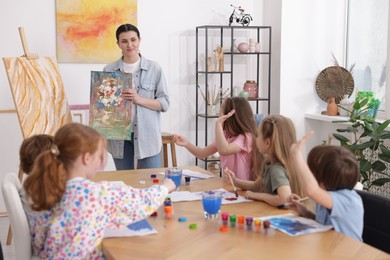 Photo of Kids with teacher at painting lesson indoors. Learning to draw