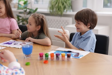 Photo of Kids painting at table indoors. Learning to draw