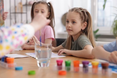 Photo of Kids painting at table indoors. Learning to draw