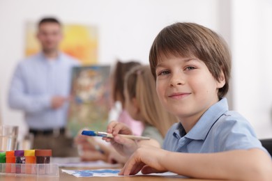 Photo of Kids with teacher at painting lesson indoors, selective focus. Learning to draw
